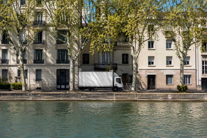 Camion de déménagement à l’arrêt le long d’un canal bordé d’arbres
