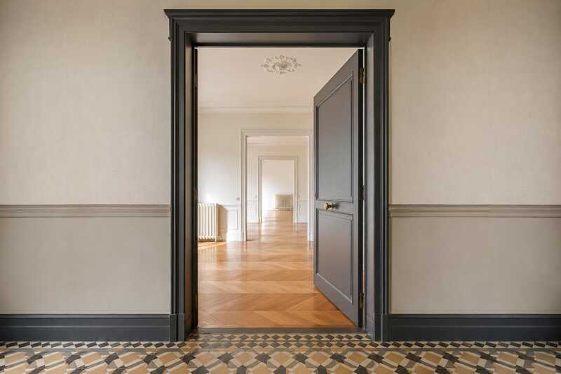 Palier d’étage à carrelage géométrique et porte ouverte sur un logement vide