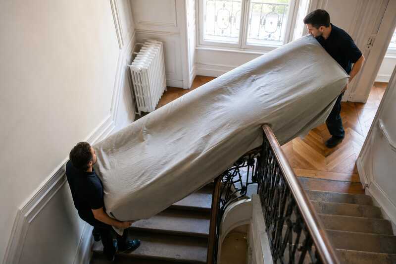Portage d’un canapé sous housse dans une cage d’escalier