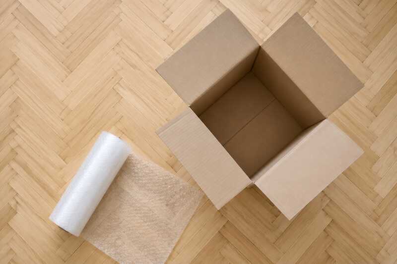 Carton ouvert et rouleau de papier bulle déroulé sur un parquet clair