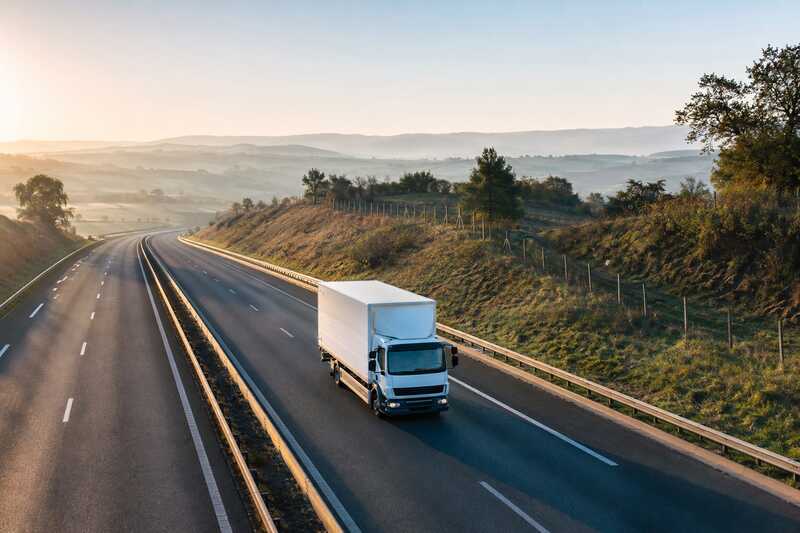 Camion de déménagement sur une autoroute traversant un paysage de collines